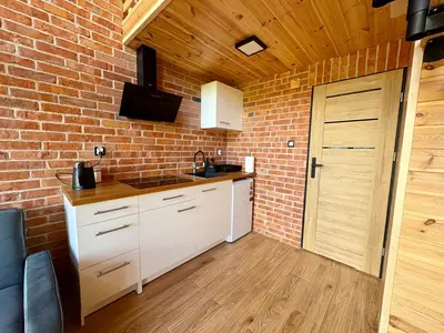 a kitchen with white cabinets and a brick wall at Beskid Barns - Domek z Balią i Widokiem na Babią Górę in Jordanów
