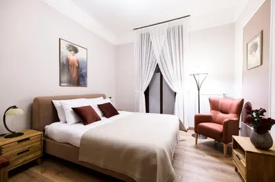 a white bedroom with a bed and a chair at Klimatyzowany apartament Dworzec Główny Stare Miasto in Kraków