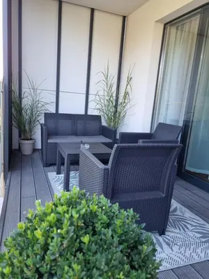 a patio with wicker chairs and tables on a balcony at Aurum Apartment in Oświęcim