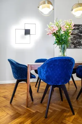 a dining room table with blue chairs and a vase of flowers at Househost Apartment Bogusławskiego 76 in Kraków