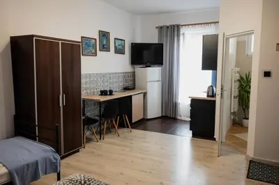 a room with a bed and a desk and a kitchen at Funny Apartment in Kraków