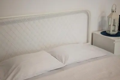 a bed with a white headboard and a night stand at Funny Apartment in Kraków