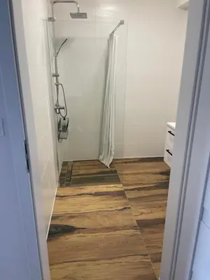 a bathroom with a shower and a wooden floor at Solny apartament