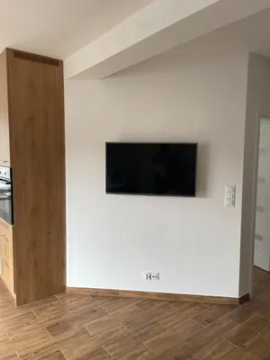 a living room with a flat screen tv on a white wall at Solny apartament