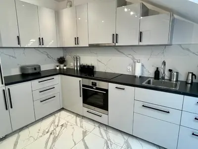 a white kitchen with white cabinets and black counter tops at Kraków Litewska Vintage in Kraków