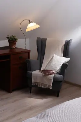 a room with a chair and a desk and a lamp at Apartamenty Pod Bocianem in Ojców