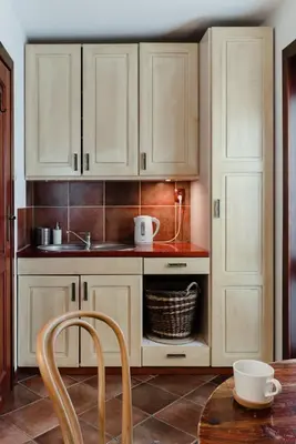 a kitchen with white cabinets and a sink and a table at Apartamenty Pod Bocianem in Ojców