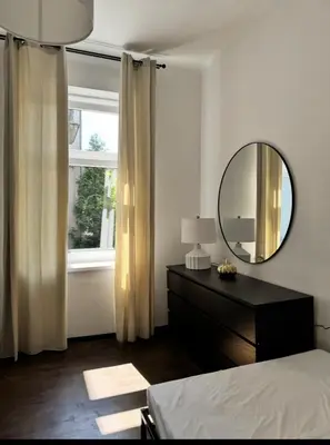 a bedroom with a mirror and a dresser and a window at Urban rooms in Kraków