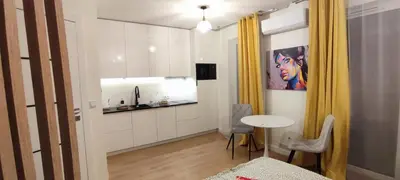 a room with a table and a kitchen with yellow curtains at Wieliczka Apartment in Czarnochowice