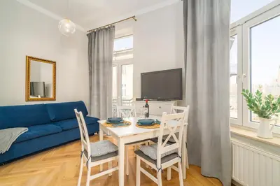 a living room with a blue couch and a table with a tv at Art Deco Elegance in Kraków
