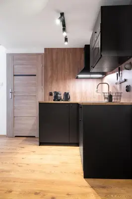 a kitchen with black appliances and a wooden floor at Househost Apartment Plac Wolnica 9 in Kraków