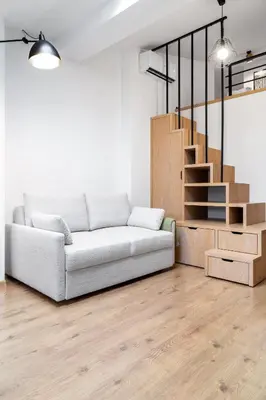 a living room with a couch and a wooden staircase at Househost Apartment Plac Wolnica 9 in Kraków
