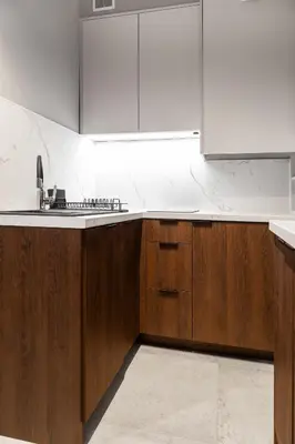 a kitchen with wooden cabinets and a white counter top at Househost Apartment Wielopole 10 in Kraków