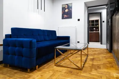 a blue couch and a glass table in a living room at Househost Apartment Wielopole 10 in Kraków