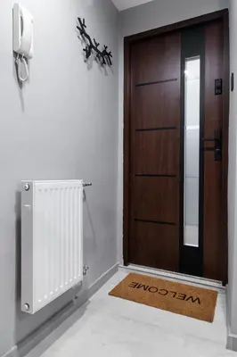 a wooden door with a rug next to a radiator at Househost Apartment Wielopole 10 in Kraków