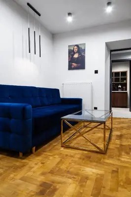 a living room with a blue couch and a glass table at Househost Apartment Wielopole 10 in Kraków