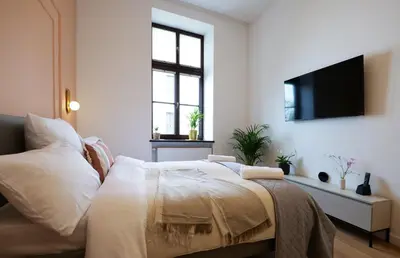 a bedroom with a bed and a flat screen tv at Apartamenty Złota Brama in Kraków