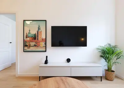 a white living room with a tv on a white wall at Apartamenty Złota Brama in Kraków