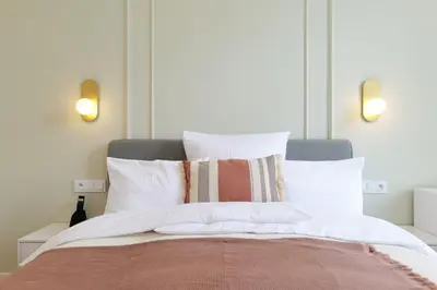 a bedroom with a bed with white sheets and pillows at Apartamenty Złota Brama in Kraków