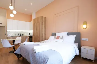 a bedroom with a large white bed and a kitchen at Apartamenty Złota Brama in Kraków