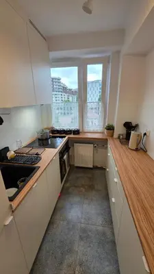 a kitchen with white cabinets and a wooden counter top at Apartament Boho 23 in Kraków