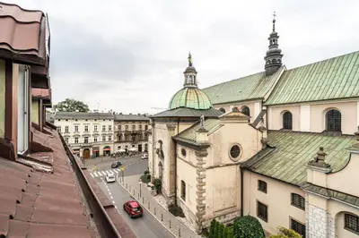 a view of a building with a red car on a street at RentPlanet - Apartament Garbarska in Kraków
