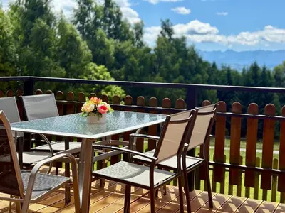 a table with chairs and a vase of flowers on a balcony at Domek Buflak in Nowy Targ