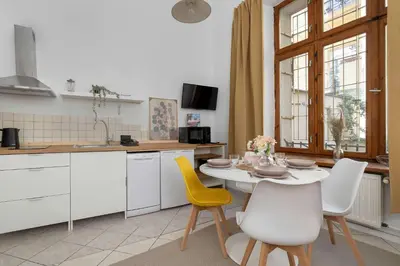 a kitchen with a white table and yellow chairs at Charming Apartment with Mezzanine near Old Town in Cracow by Noclegi Renters in Kraków