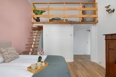 a bedroom with a loft bed and a spiral staircase at Charming Apartment with Mezzanine near Old Town in Cracow by Noclegi Renters in Kraków