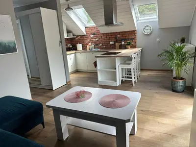 a living room with a table and a kitchen at Apartament Buldog in Zawoja