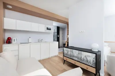 a kitchen and living room with white cabinets and a tv at City of the Kings-Riverside K22M31 in Kraków