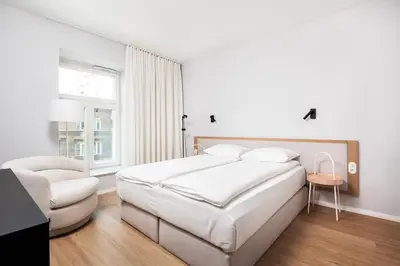 a white bedroom with a large bed and a chair at City of the Kings-Riverside K22M16 in Kraków