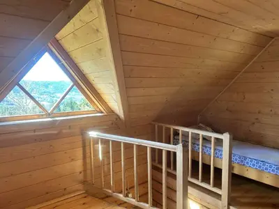 an attic room with a bed and a window at Samotnia w Górach Odludzie Domek in Ochotnica Górna
