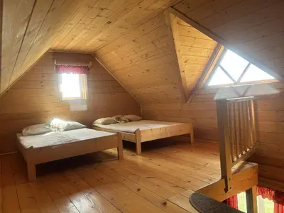 an attic room with two beds and a window at Samotnia w Górach Odludzie Domek in Ochotnica Górna
