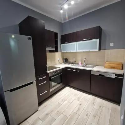 a kitchen with a stainless steel refrigerator and wooden floors at Apartament Anna in Kraków