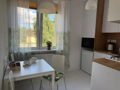 a kitchen with a white table and a window at Apartament Żabie Oczko in Zator
