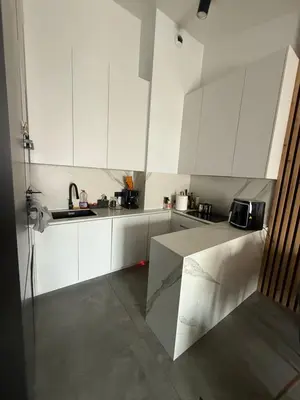 a white kitchen with white cabinets and a sink at Zablocie Apartment near to Schindler Fabric - 48m2 in Kraków