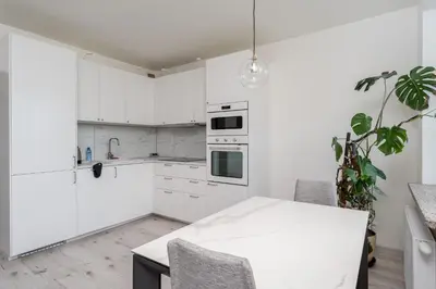 a kitchen with white cabinets and a white table at Grzegórzki Chic Studio by BookingHost in Kraków