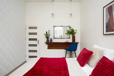a bedroom with a bed with red pillows and a mirror at LORETO 2 by Cozyplace in Kraków