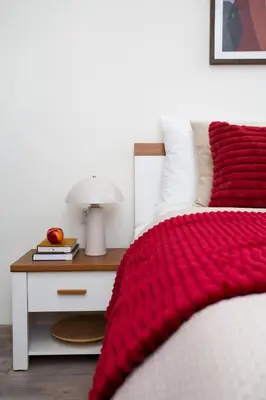 a red blanket on a bed next to a nightstand at LORETO 2 by Cozyplace in Kraków
