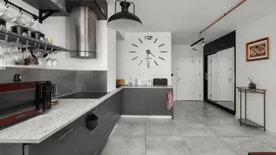 a large kitchen with a large clock on the wall at Limanowskiego Modern Studio by BookingHost in Kraków