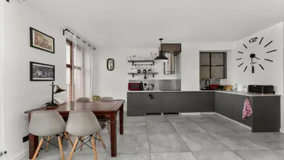 a kitchen and dining room with a table and a clock at Limanowskiego Modern Studio by BookingHost in Kraków