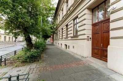 an empty sidewalk next to a building with a tree at Limanowskiego Modern Studio by BookingHost in Kraków