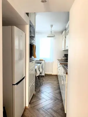 a kitchen with white cabinets and a refrigerator at Comfortable and large apartment in Kraków