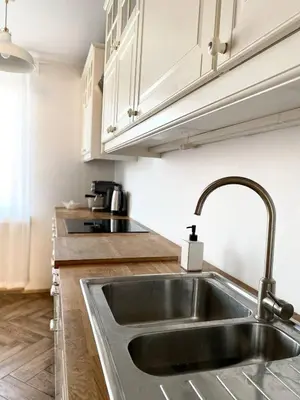 a stainless steel sink in a kitchen with white cabinets at Comfortable and large apartment in Kraków