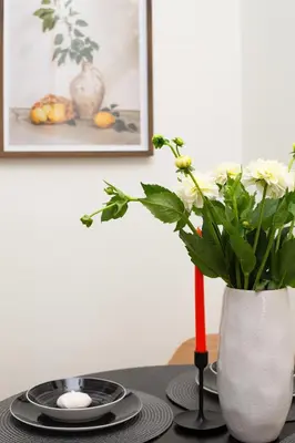 a table with a vase with white flowers and a candle at LORETO 3 by Cozyplace in Kraków