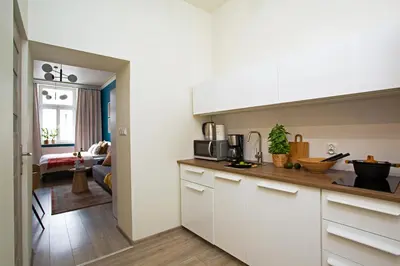 a kitchen with white cabinets and a living room at LORETO 3 by Cozyplace in Kraków