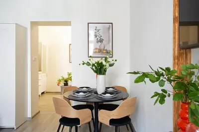 a dining room table with chairs and a vase with flowers at LORETO 3 by Cozyplace in Kraków