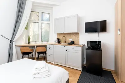 a small kitchen with a bed and a table with chairs at Kazimierz Comfort Apartment- Starowiślna 54 in Kraków