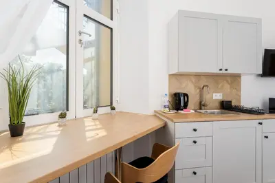 a kitchen with white cabinets and a wooden counter top at Kazimierz Comfort Apartment- Starowiślna 54 in Kraków